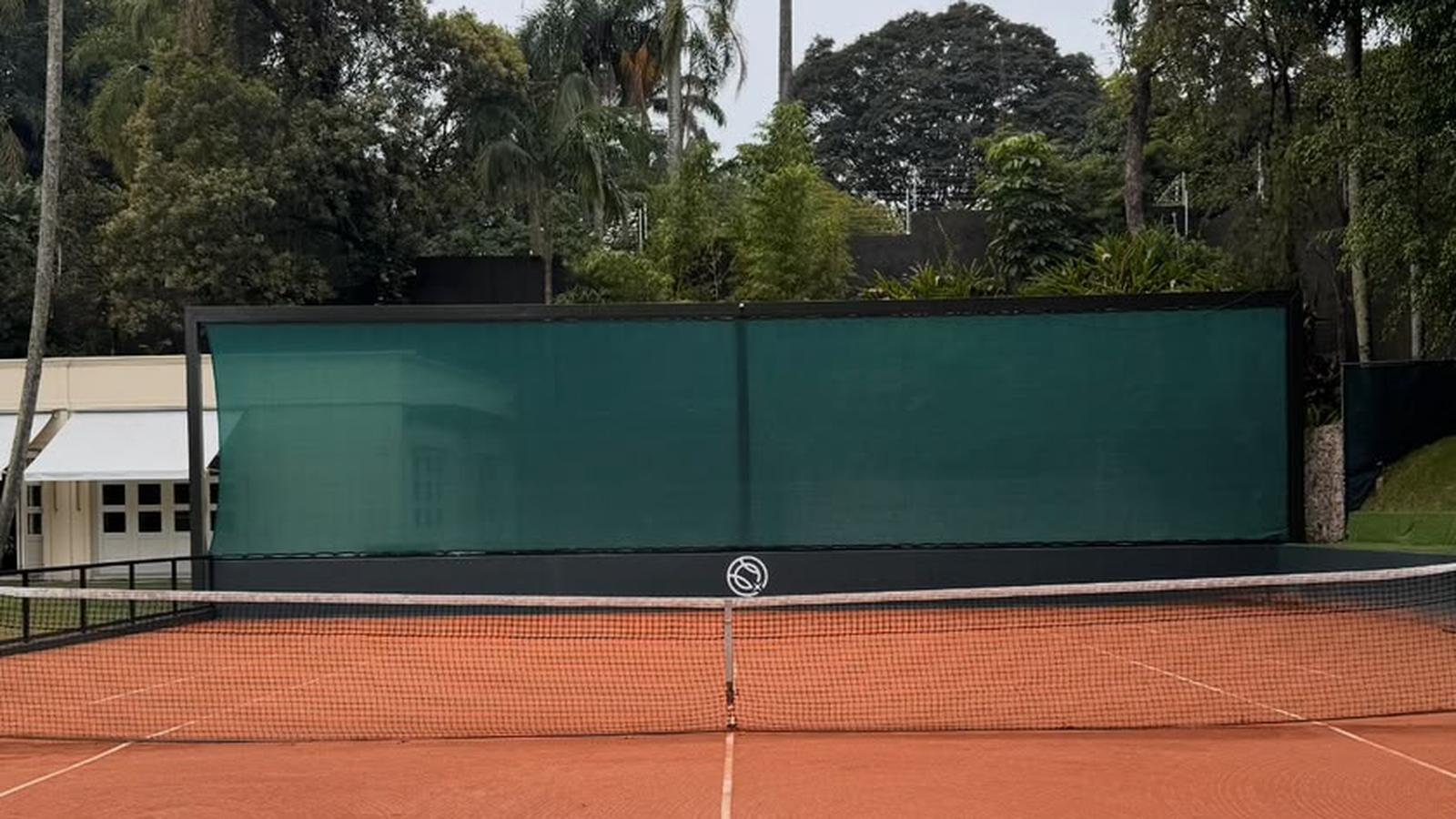 Quadra de saibro com fechamento em tela verde escura, tensionada em pano único