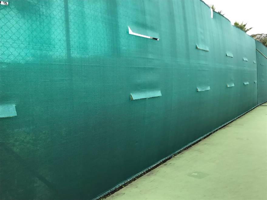 Tela de fechamento verde instalada ao longo da quadra, com ilhoses reforçados.