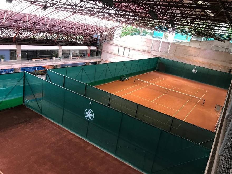 Arena coberta com quadras numeradas e tela padronizada com o logo do clube.