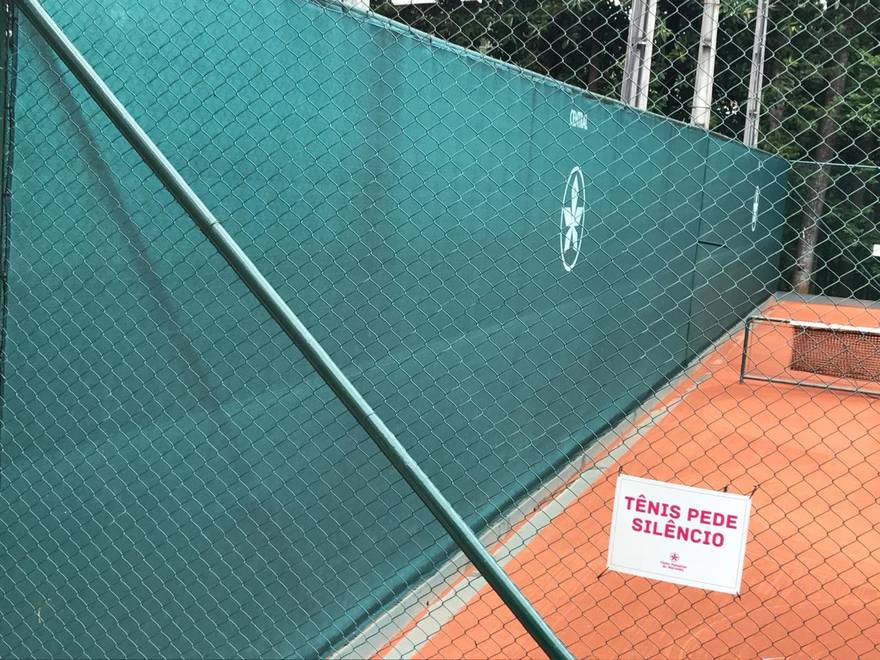 Detalhe da tela instalada sobre o alambrado, com o brasão do clube em recorte na malha.